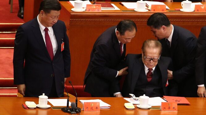 Asistentes ayudan al ex presidente Jiang Zemin a levantarse junto a Xi Jinping, ayer en Pekín.