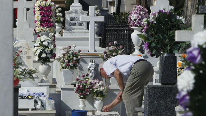 Un hombre arregla la lápida de un ser querido.