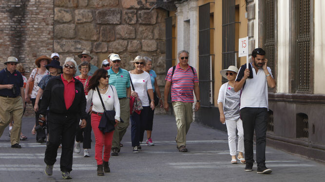 Visitantes siguen a un guía turístico por la zona monumental de la capital