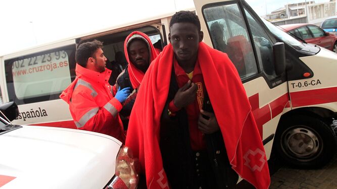 Un voluntario de Cruz Roja atiende a dos de los inmigrantes que llegaron ayer al puerto de Tarifa.