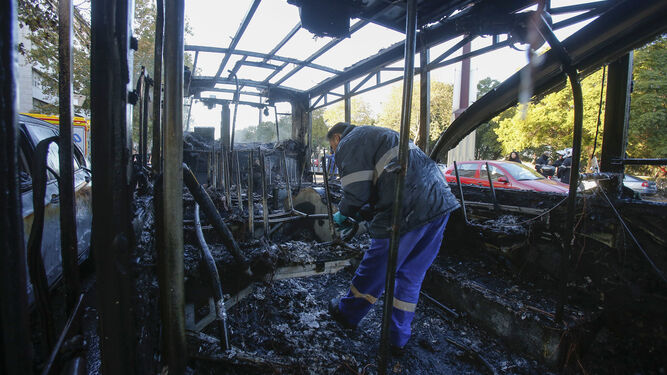 Una persona inspecciona el interior del autobús que quedó totalmente calcinado tras el incendio.