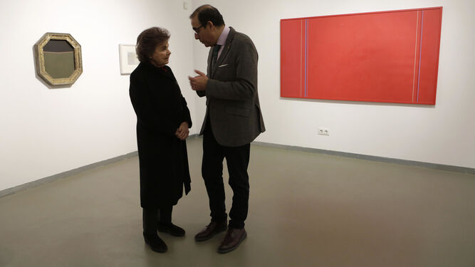 Carmen Laffón conversa con el rector de la Universidad de Sevilla ante un lienzo rojo de Pepe Soto.