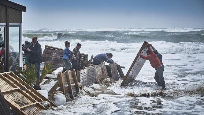Trabajadores de un chiringuito de Cádiz tratan de montar un dique para frenar la entrada del agua.
