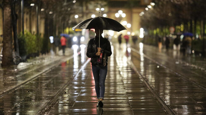 Un ciudadano camina bajo la lluvia por la calle San Fernando de la capital.