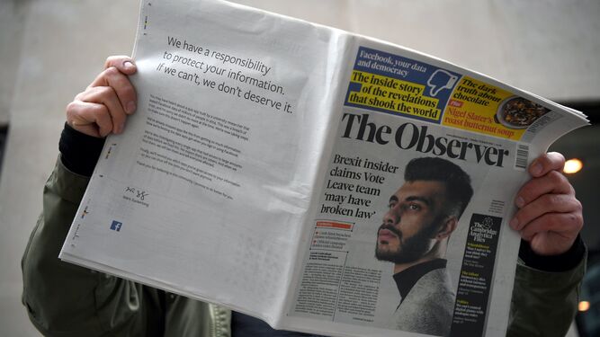 Un hombre lee un periódico británico en el que Zuckerberg publicó sus disculpas en la contraportada.