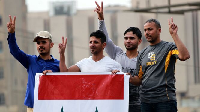Partidarios del régimen sirio portan una bandera del país en Bagdad (Iraq).