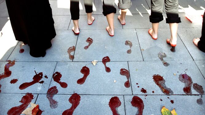 Varias mujeres dejan las huellas de sus pies teñidos de rojo durante una manifestación en Sevilla.
