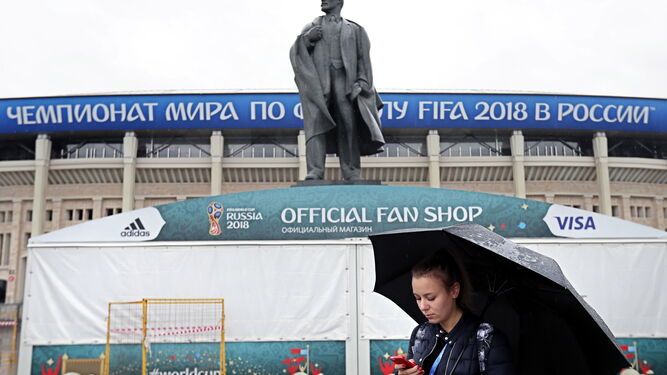 Una joven mira su móvil bajo la lluvia, ayer, ante una estatua de Lenin en Moscú.