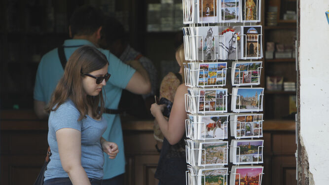 Una joven mira un estante con postales de la capital hispalense.