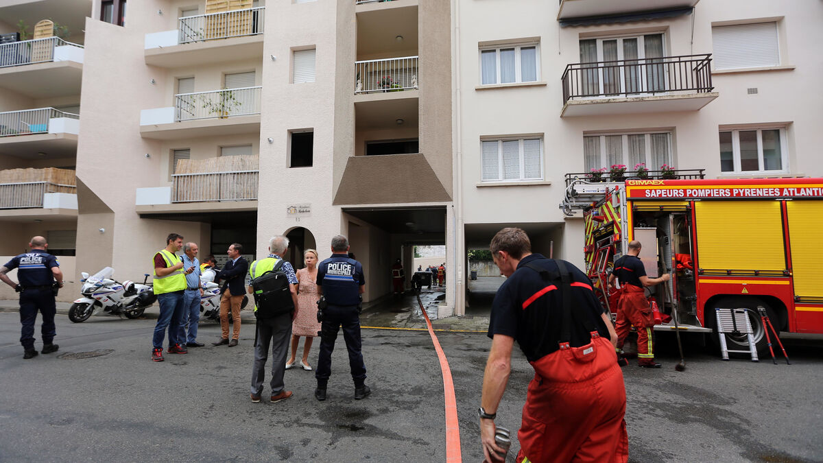 Bomberos y policías trabajan a las puertas del bloque de pisos donde ha tenido lugar el crimen en Pau.