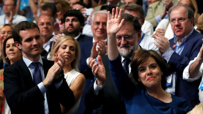 Soraya Sáenz de Sanmtamaría saluda a los asistentes al congreso del PP mientras Pablo Casado yMariano Rajoy la aplauden.