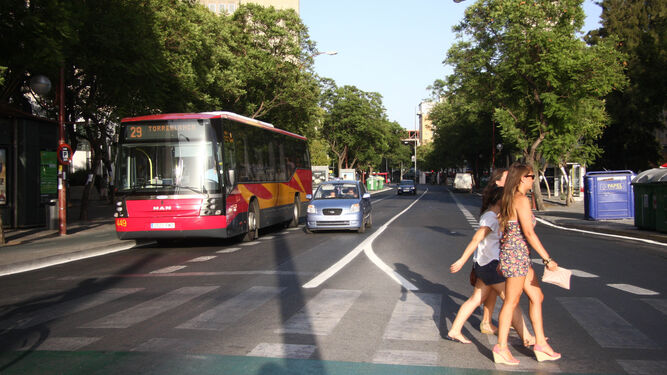 Mujeres cruzan frente a un bus de Tussam