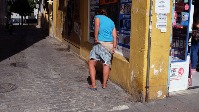 Una mujer se sube el pantalón en una calle de la Macarena.