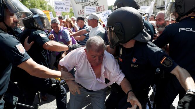 Uno de los pensionistas intentando traspasar la barrera policial.