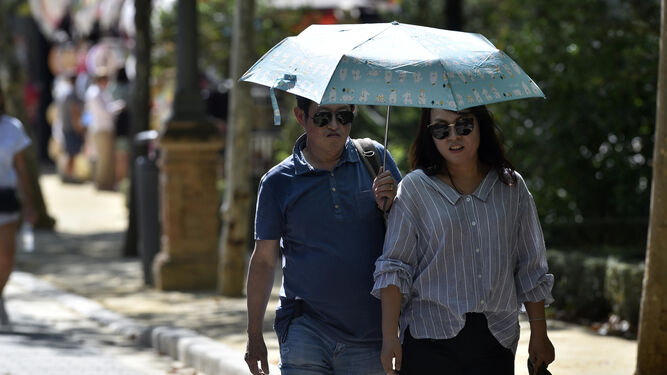 Dos turistas pasean protegiéndose del sol con un paraguas