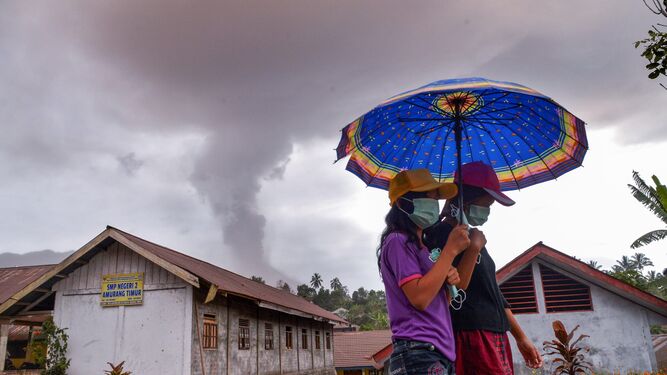 Dos jóvenes caminan mientras el volcán Sotupan sigue en erupción al norte de la isla de Célebes.