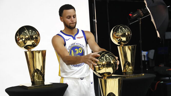 Stephen Curry posa con los tres trofeos de los Warriors