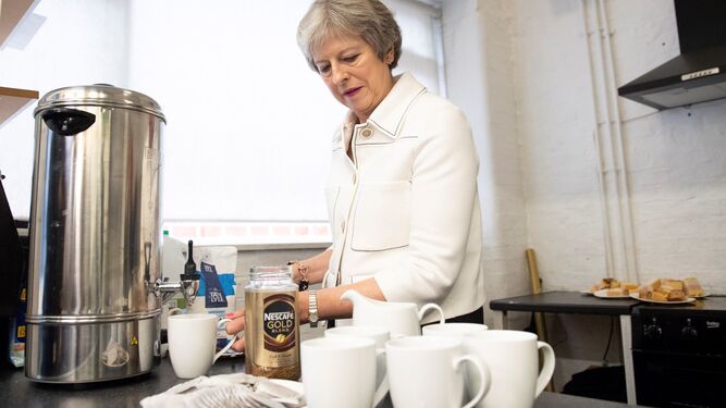 Theresa May prepara un café en una reunión con una asociación benéfica.