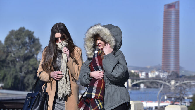 Dos jóvenes se protegen del frío en Sevilla.