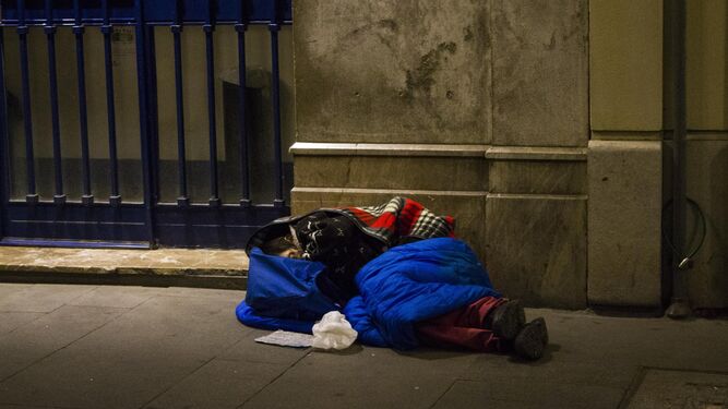 Una persona sin hogar duerme en plena calle liada en mantas.