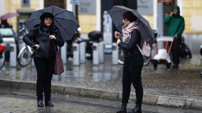Dos mujeres se protegen de la lluvia con un paraguas en Sevilla.