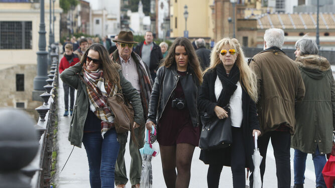 Varias personas caminan abrigadas por Sevilla.