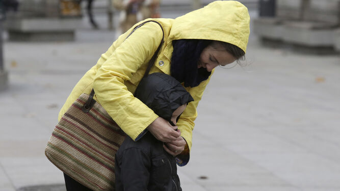 Una madre abriga a su hijo un día de frío en Sevilla.