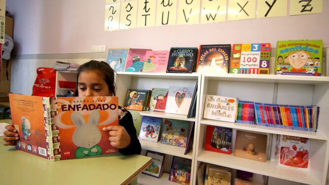 Una niña lee en una biblioteca.