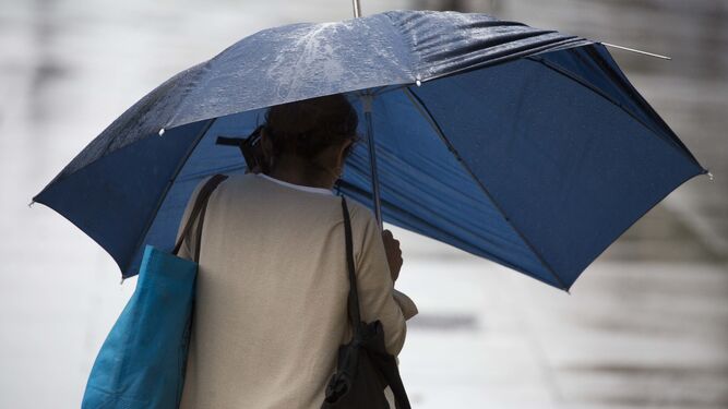 Una mujer con un paraguas por el centro.