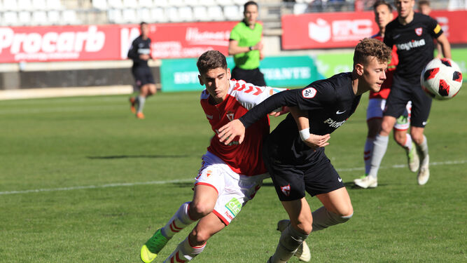 El sevillista Javi Vázquez intenta proteger el balón ante un jugador del Murcia.