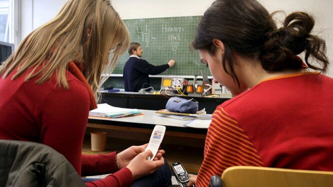 Adolescentes con móviles en clase.