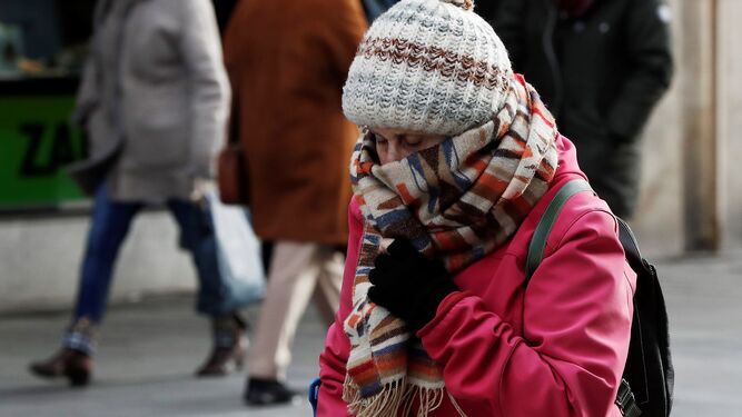 Una mujer se cubre con gorro, guantes y bufandas.