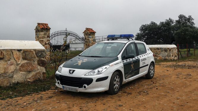 Un coche de la Guardia Civil, junto a la entrada de la finca Las lapas, en Guillena, donde ocurrieron los hechos.