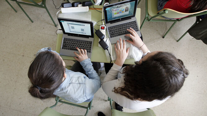 Dos chicas estudian con ordenadores en un instituto de Granada.
