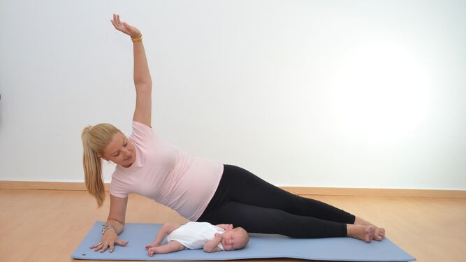 Una mujer practica ejercicios con su bebé para favorecer su recuperación post parto.