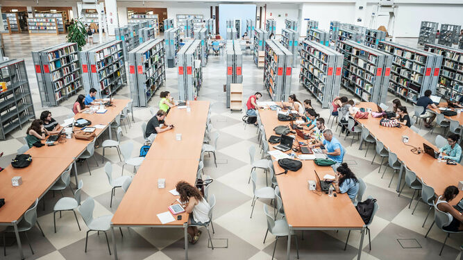 Varios universitarios en una biblioteca.