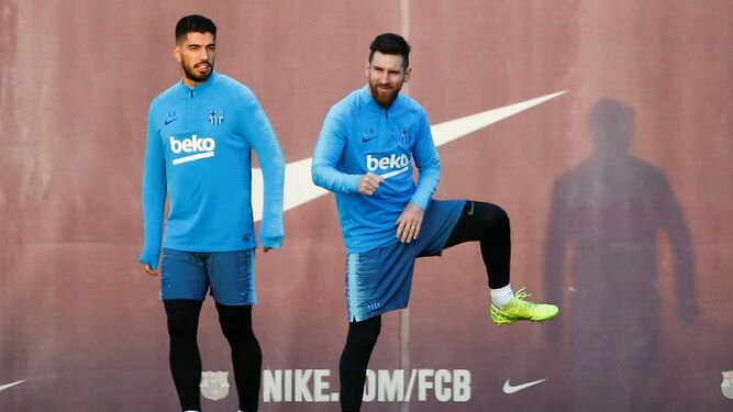 Messi se estira junto a Luis Suárez en un entrenamiento.