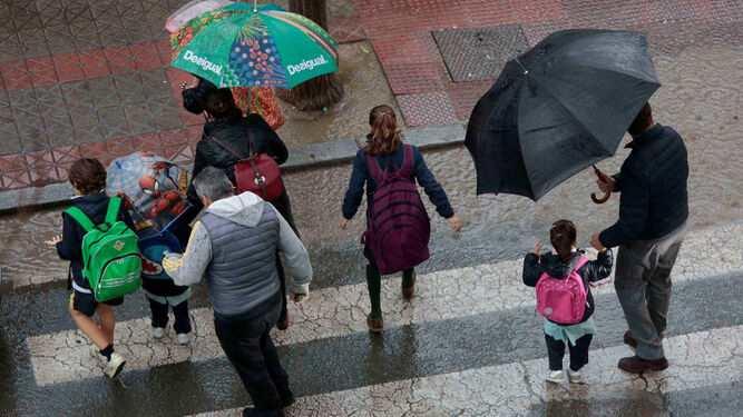 Varias personas se protegen de la lluvia en Sevilla.