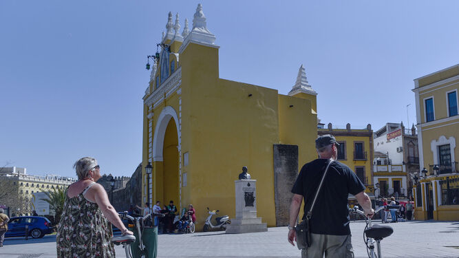 Dos viajeros se acercan en bicicleta al Arco de la Macarena.