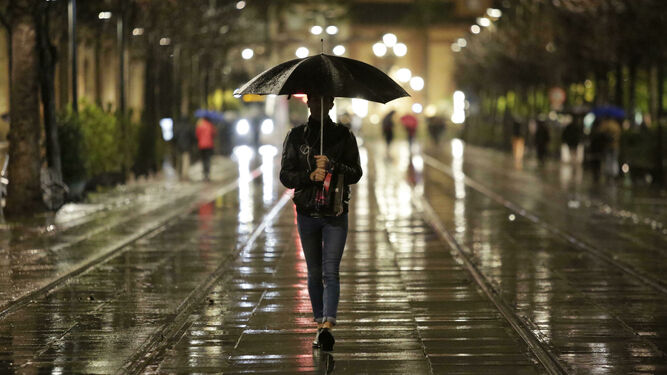 Joven con paraguas caminando por el centro de la ciudad