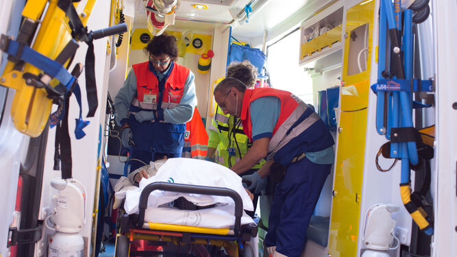 Dos profesionales de cuidados críticos y urgencias del Área de Gestión Sanitaria Sur de Sevilla atienden a un paciente en una ambulancia.