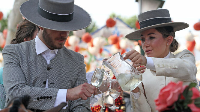 Jinete y amazona compartiendo una jarra de rebujito por el Real de la Feria de abril.