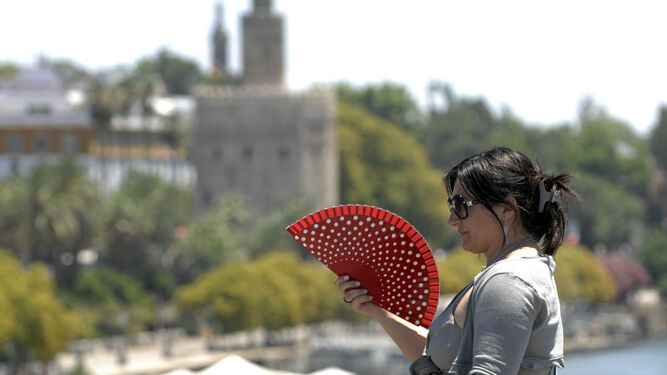 Una mujer se abanica para aliviar el calor en Sevilla.