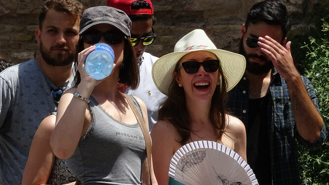 Varios turistas combaten el calor con sombreros, botellas de agua fría y abanicos.
