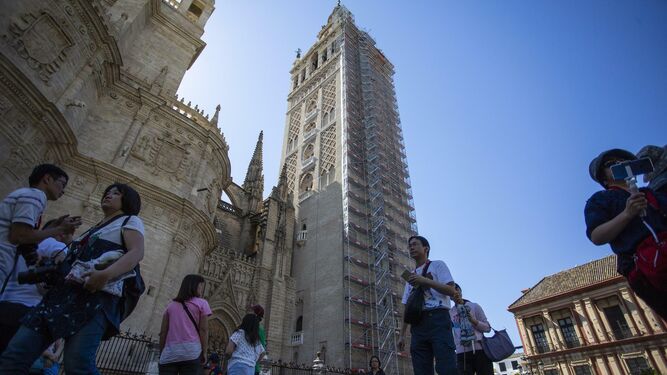 Un grupo de turistas pasea ante la Catedral y la Giralda.