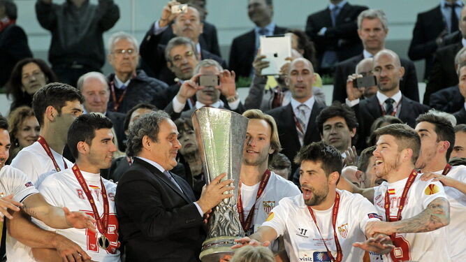 Michel Platini, presidente de la UEFA en 2014, entrega la copa de campeón a Rakitic.