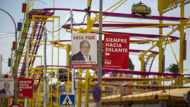 Carteles electorales de Toscano, con la perspectiva de la montaña rusa de la Feria, que se celebró hasta el domingo en el municipio.