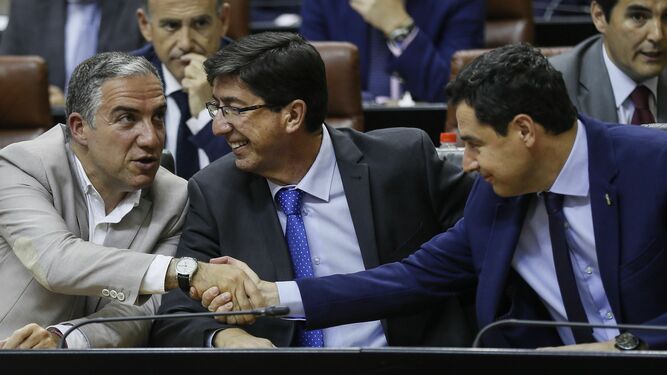 Juanma Moreno saluda a Elías Bendodo y Juan Marín, al inicio del pleno del Parlamento