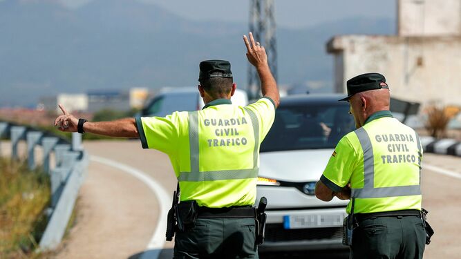 Dos guardias civiles de Tráfico hacen indicaciones a un conductor, en una imagen de archivo.