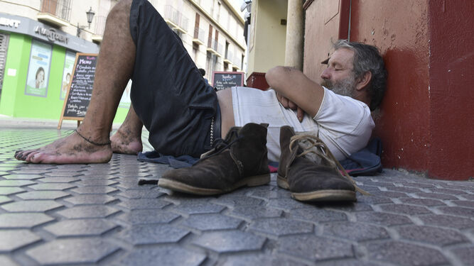 Un hombre descansa en el suelo de una céntrica calle de la ciudad.